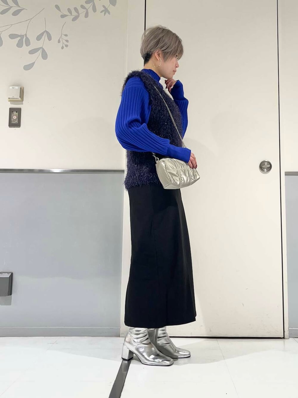 シルバー系のブーツ、ブルー系のベスト、ブルー系のニット/セーターを着用したレディースの冬コーディネートの2枚目の写真