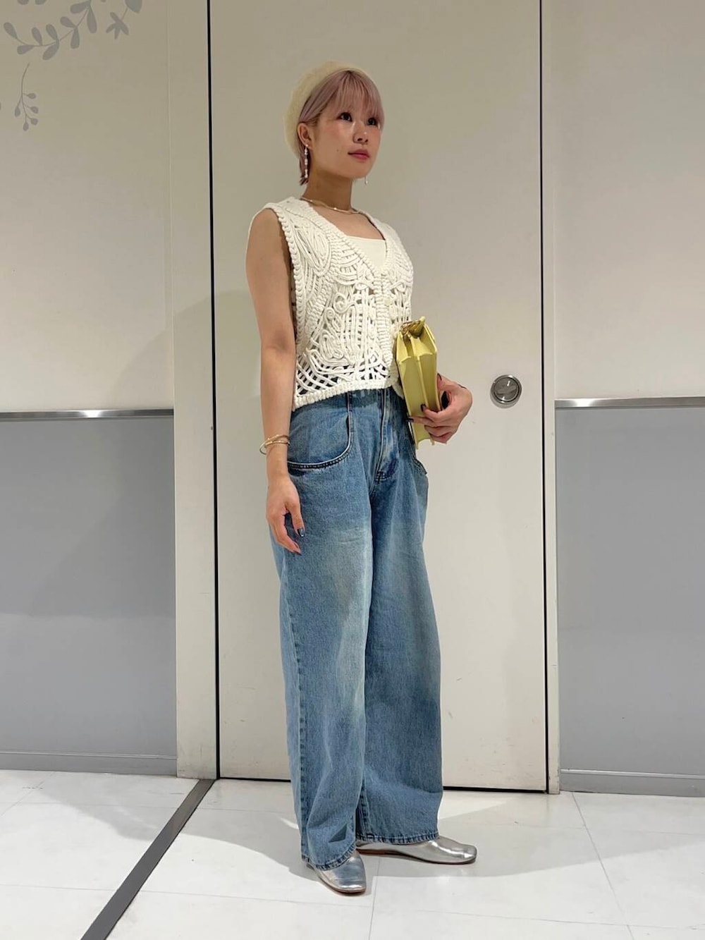 ブルー系のデニムパンツ、ホワイト系のキャミソール、ホワイト系のベストを着用したレディースの秋コーディネートの2枚目の写真