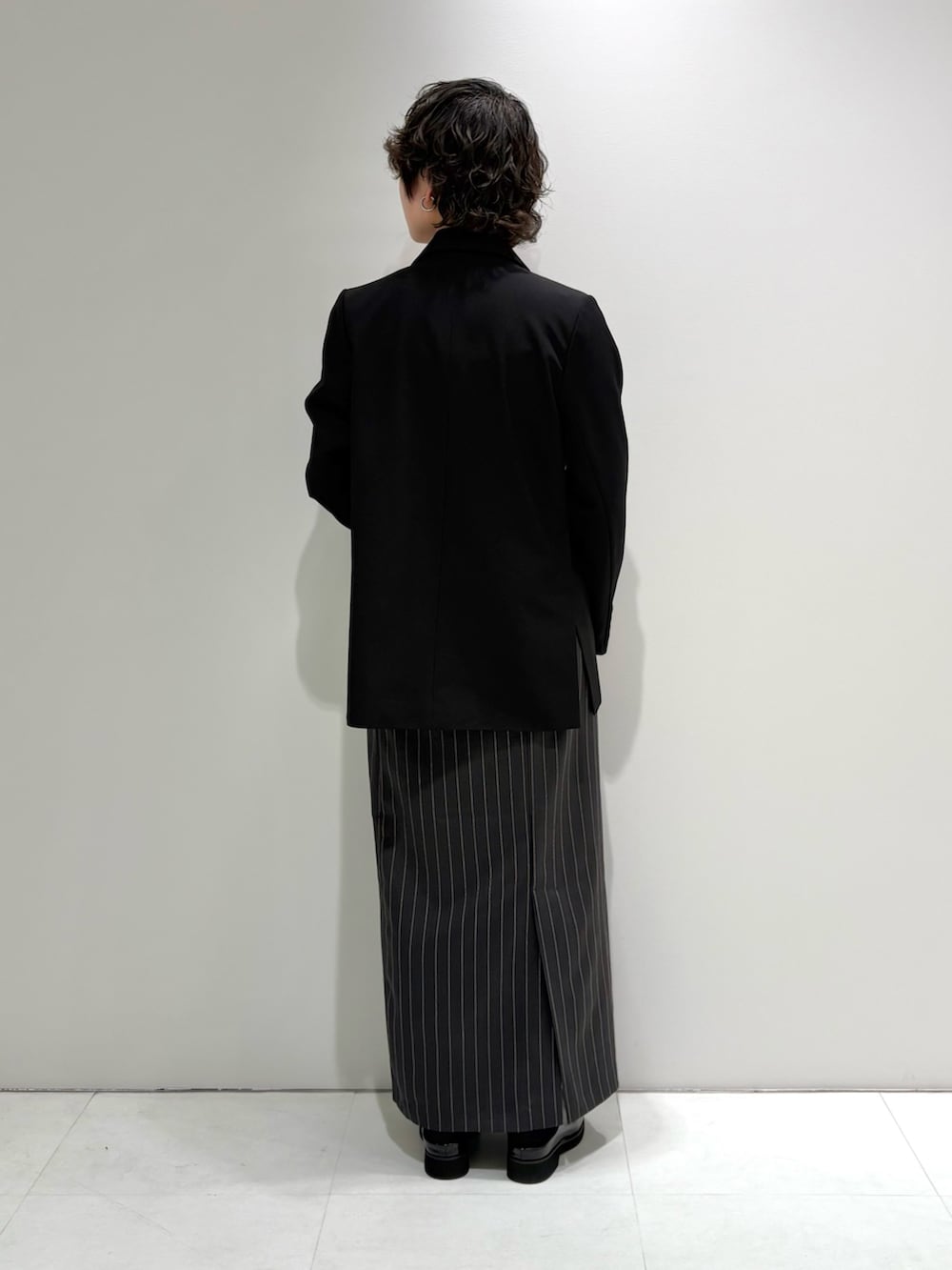 ブラック系のテーラードジャケット、グレー系のスカート、ブラック系のサンダルを着用したレディースの春コーディネートの4枚目の写真