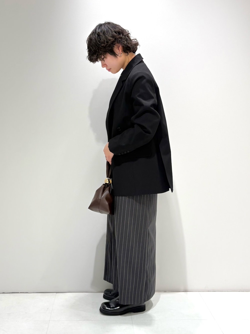 ブラック系のテーラードジャケット、グレー系のスカート、ブラック系のサンダルを着用したレディースの春コーディネートの3枚目の写真