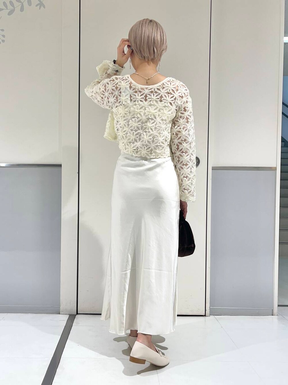 ホワイト系のローファー、ホワイト系のキャミソール、ブラウン系のハンドバッグを着用したレディースの秋コーディネートの2枚目の写真