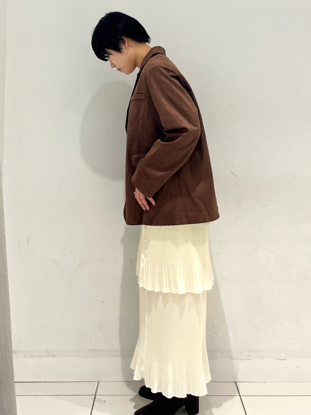 ブラウン系のその他アウター、ホワイト系のスカート、ブラウン系のブーツを着用したレディースの秋コーディネートの2枚目の写真