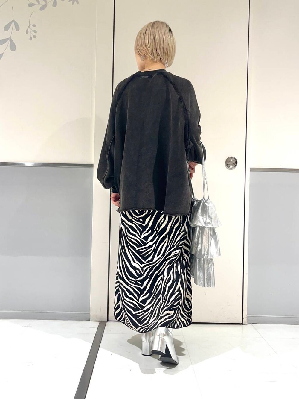 シルバー系のトートバッグ、シルバー系のブーツ、ブラック系のスカートを着用したレディースの秋コーディネートの2枚目の写真