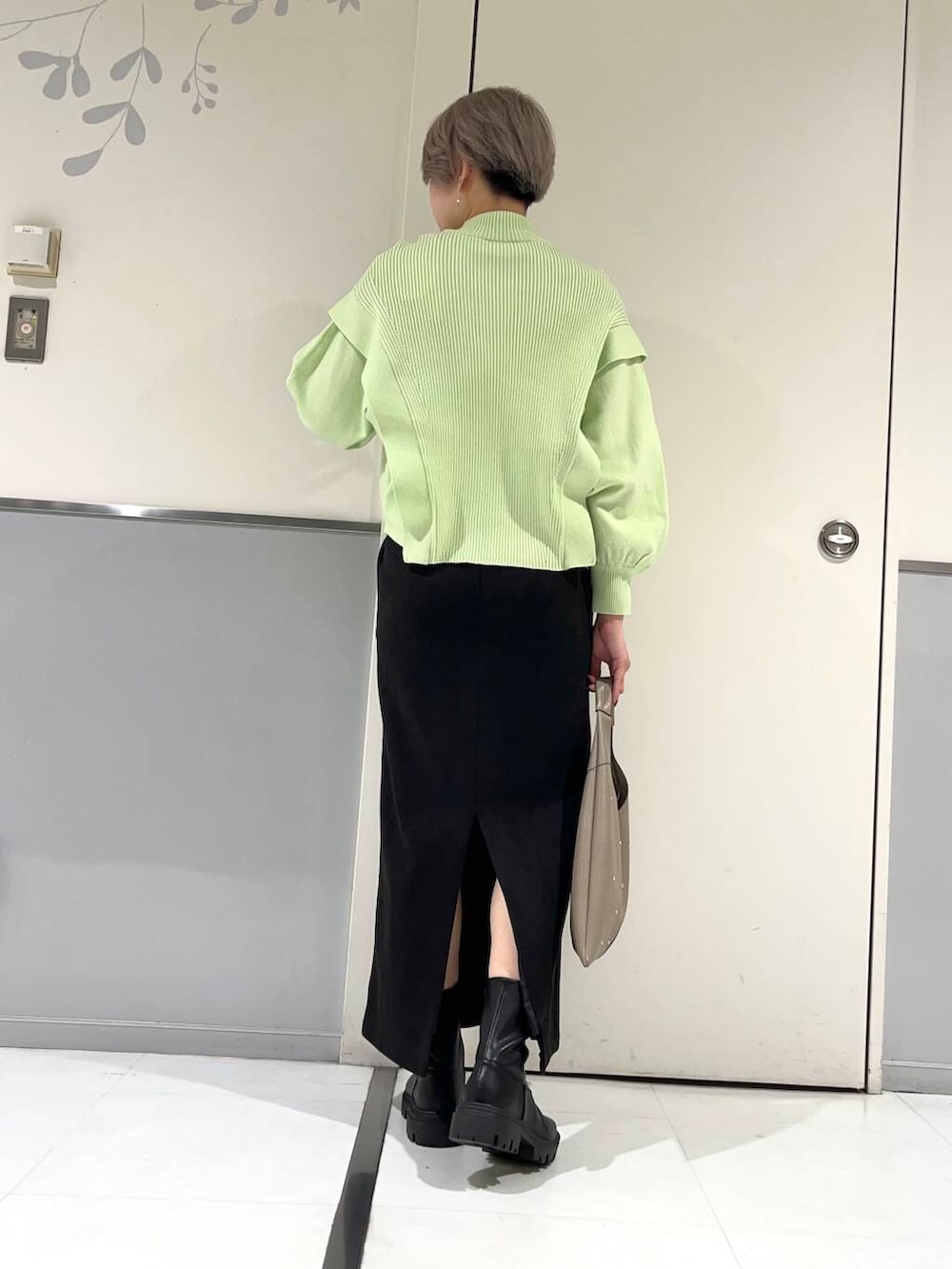 ベージュ系のトートバッグ、ブラック系のブーツ、グリーン系のニット/セーターを着用したレディースの冬コーディネートの3枚目の写真