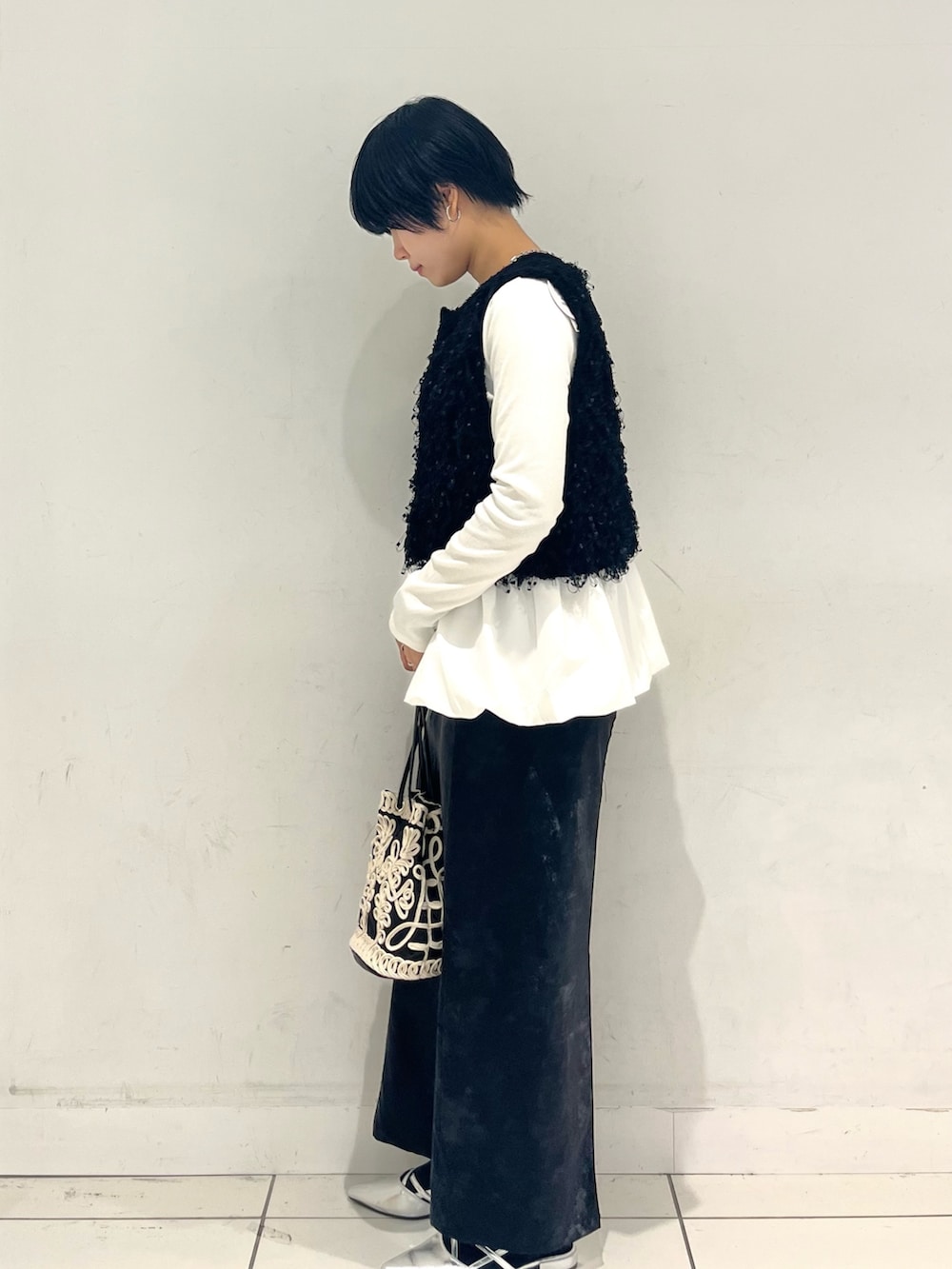 ホワイト系のニット/セーター、ホワイト系のTシャツ/カットソー、ブラック系のスカートを着用したレディースの秋コーディネートの2枚目の写真