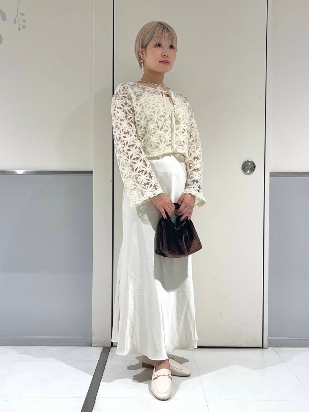 ホワイト系のローファー、ホワイト系のキャミソール、ブラウン系のハンドバッグを着用したレディースの秋コーディネートの3枚目の写真