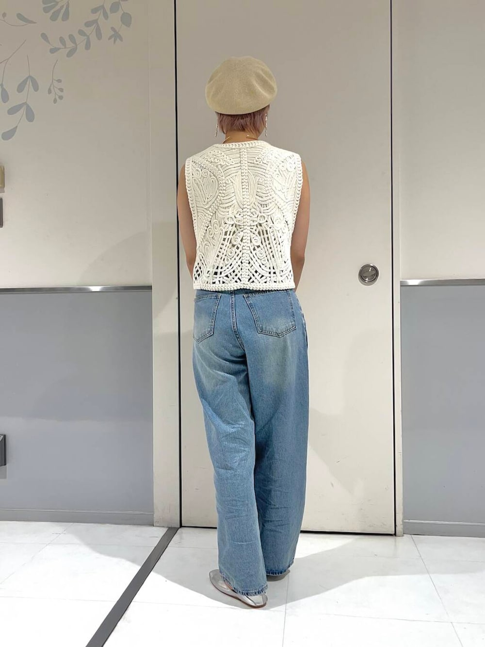 ブルー系のデニムパンツ、ホワイト系のキャミソール、ホワイト系のベストを着用したレディースの秋コーディネートの3枚目の写真