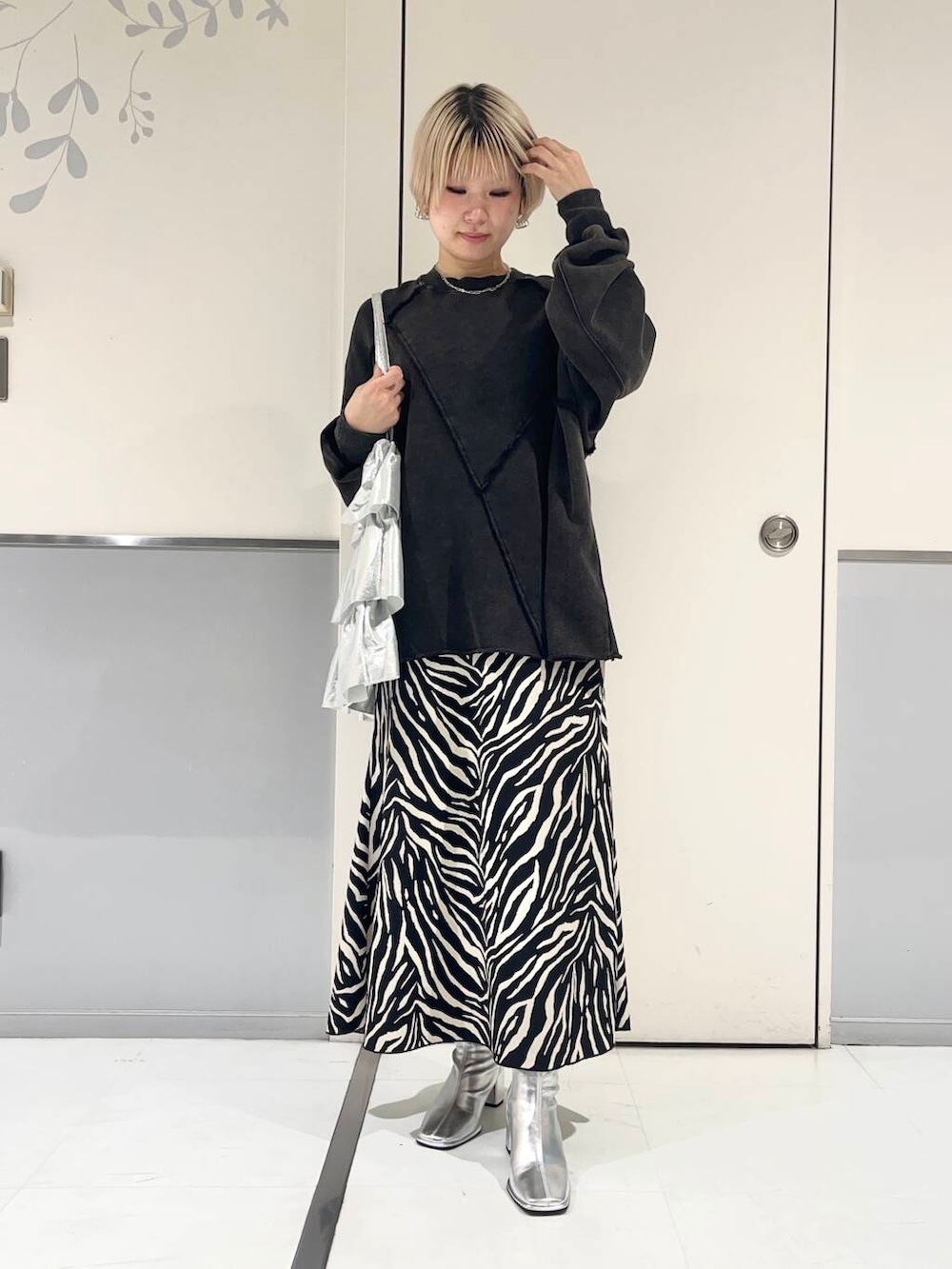 シルバー系のトートバッグ、シルバー系のブーツ、ブラック系のスカートを着用したレディースの秋コーディネートの3枚目の写真