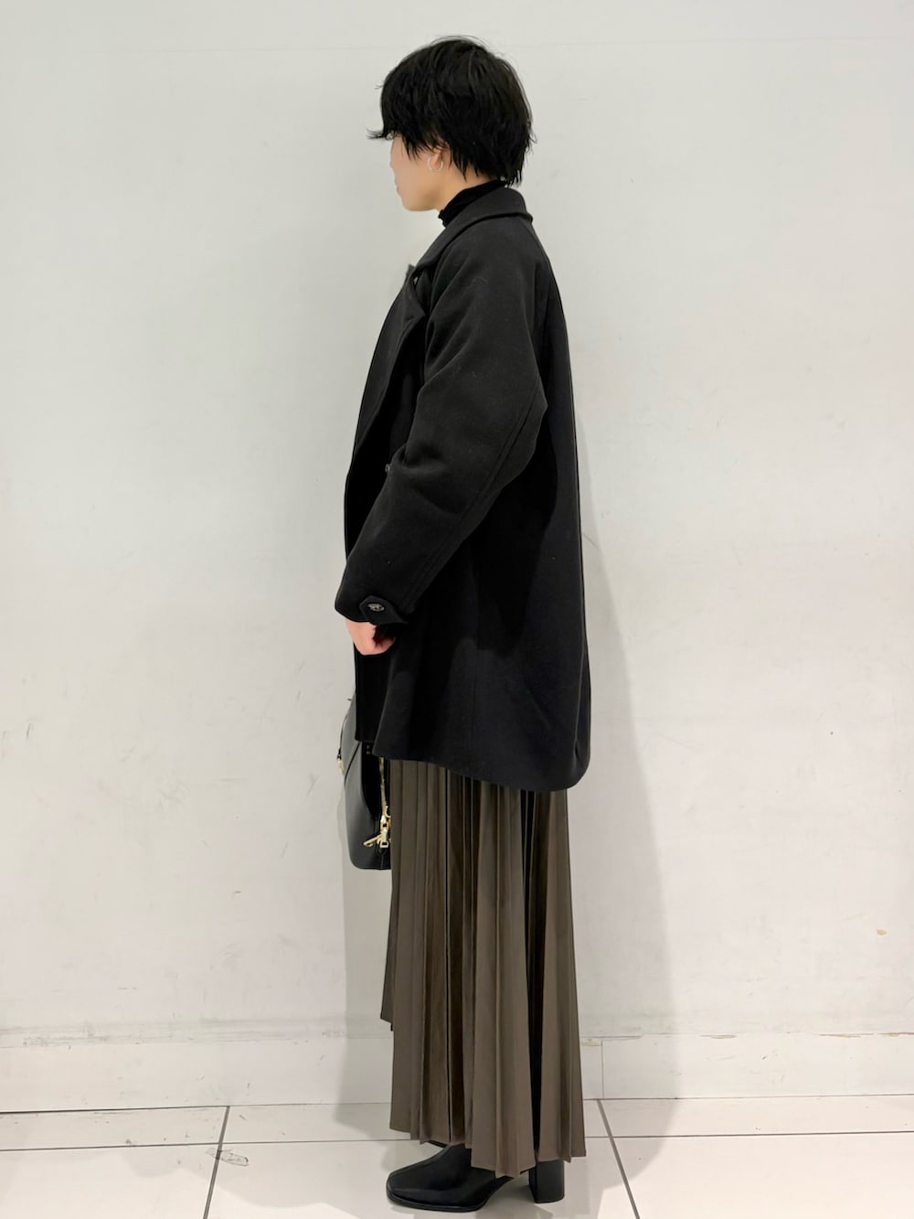 グレー系のカーディガン/ボレロ、ブラック系のTシャツ/カットソー、ブラウン系のスカートを着用したレディースの冬コーディネートの2枚目の写真