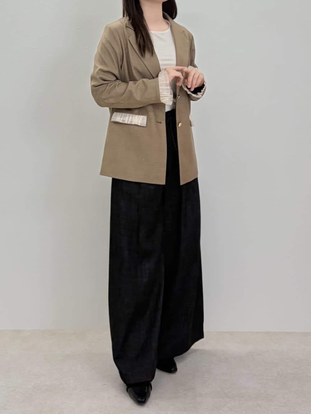 ブラック系のパンプス、ブラック系のスラックス、ブラウン系のテーラードジャケットを着用したレディースの春コーディネートの2枚目の写真