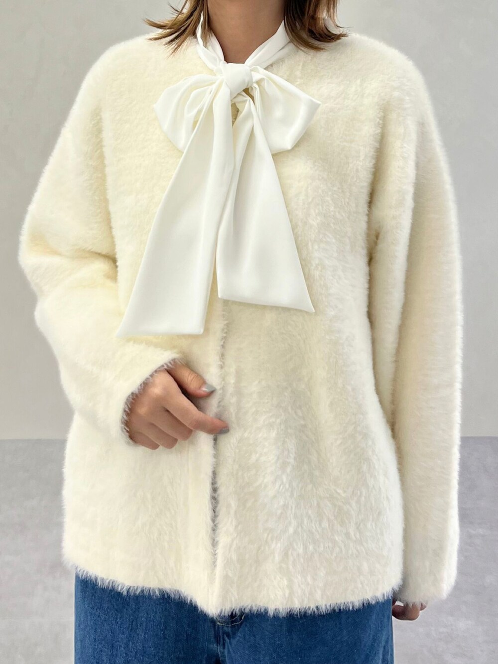 ホワイト系のシャツ/ブラウス、ブラウン系のカーディガン/ボレロ、ブルー系のデニムパンツを着用したレディースの秋コーディネートの3枚目の写真