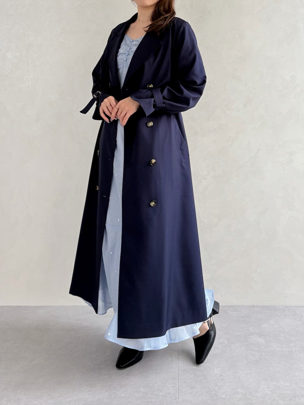 ブラック系のパンプス、ブルー系のワンピース、ブルー系のトレンチコートを着用したレディースの春コーディネートの2枚目の写真