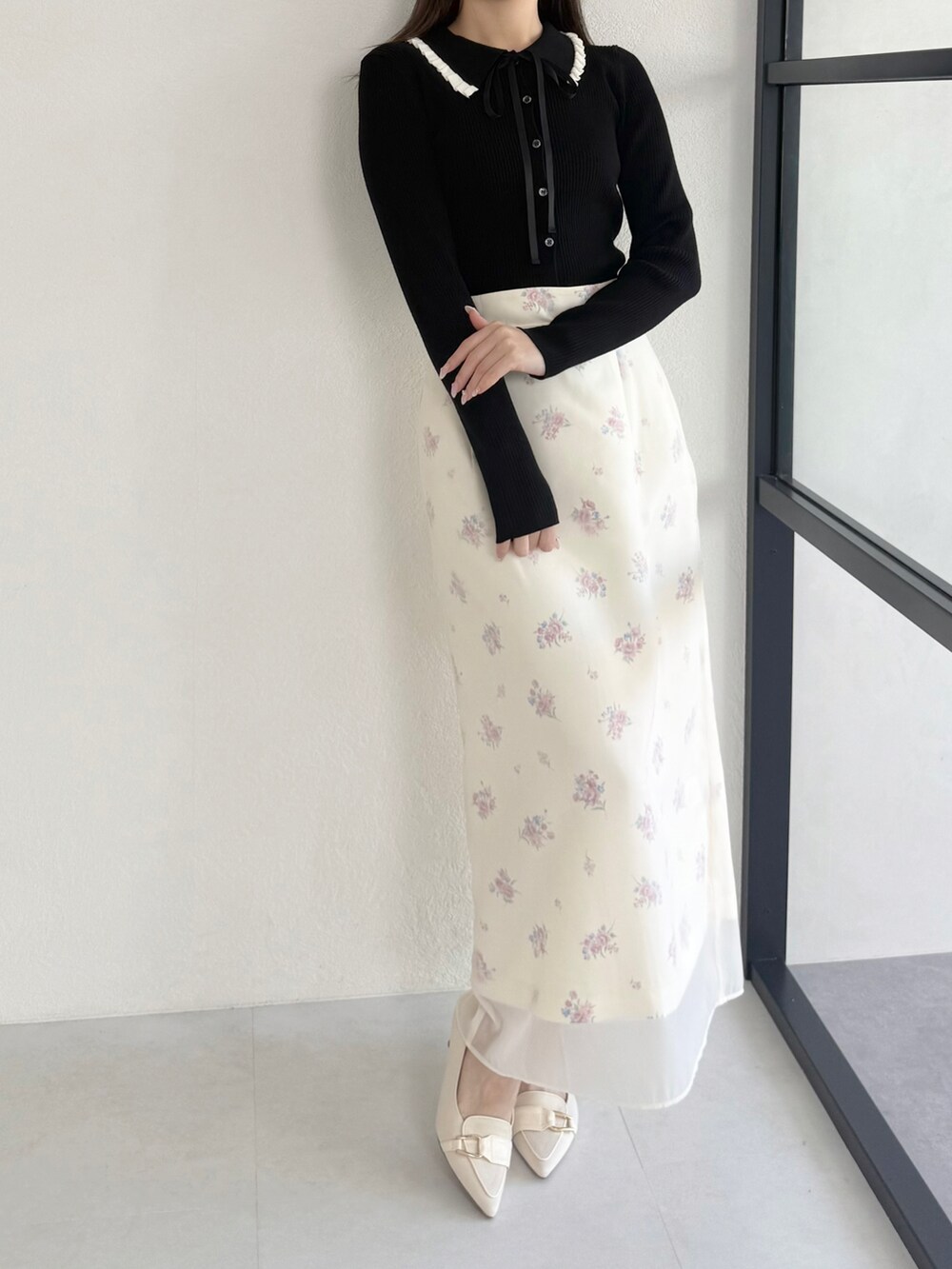 ブラック系のニット/セーター、ベージュ系のシューズ、イエロー系のスカートを着用したレディースの春コーディネートの3枚目の写真