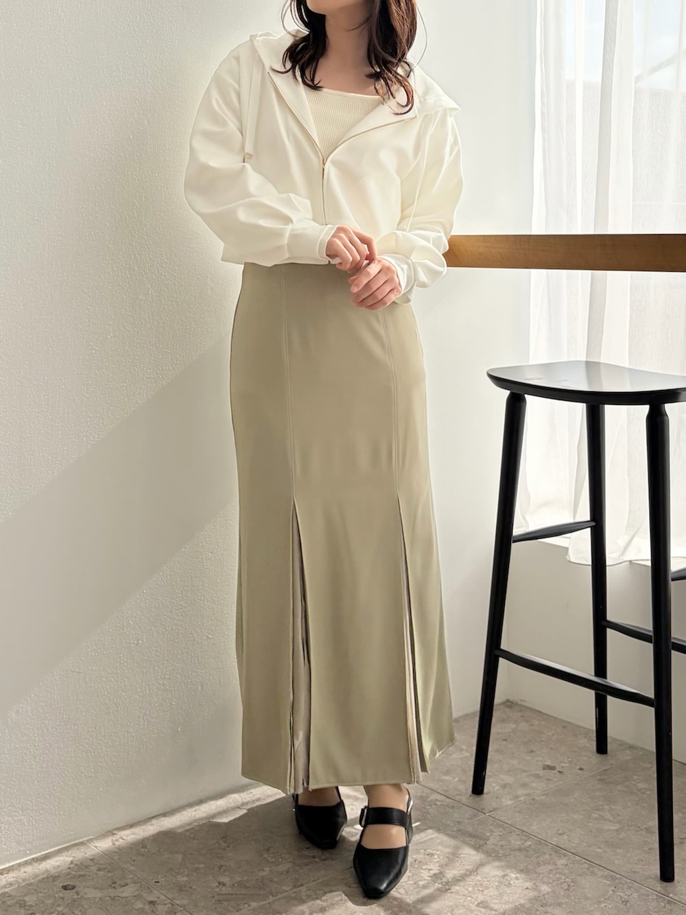 グリーン系のスカート、ブラック系のパンプス、ホワイト系のパーカーを着用したレディースの春コーディネートの3枚目の写真