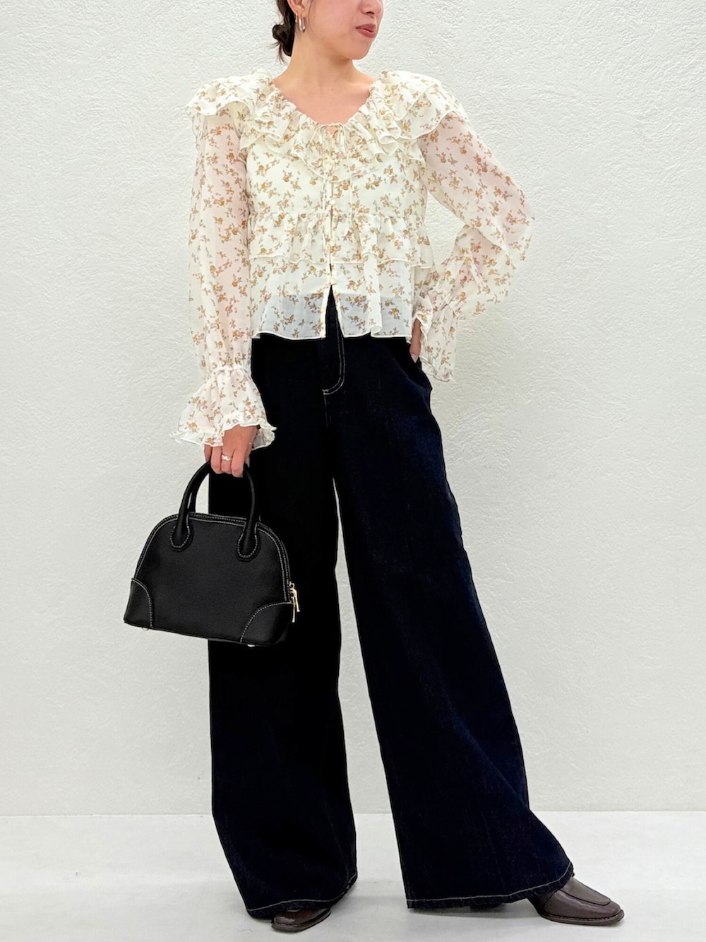 ブラウン系のパンプス、ベージュ系のシャツ/ブラウス、ブルー系のデニムパンツを着用したレディースの秋コーディネートの2枚目の写真