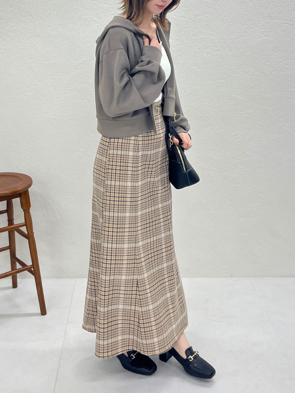 ブラウン系のパーカー、ベージュ系のスカート、ブラック系のバッグを着用したレディースの秋コーディネートの5枚目の写真