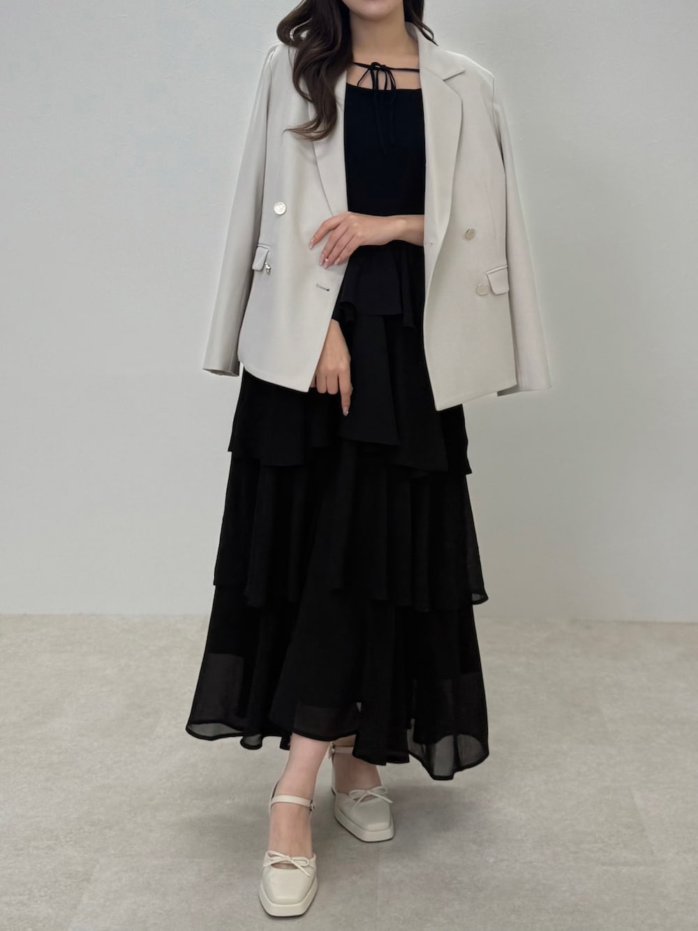 ベージュ系のテーラードジャケット、ブラック系のワンピースを着用したレディースの春コーディネートの2枚目の写真