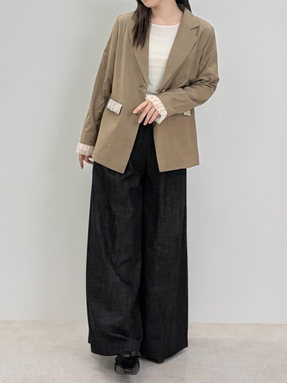 ブラック系のパンプス、ブラック系のスラックス、ブラウン系のテーラードジャケットを着用したレディースの春コーディネートの3枚目の写真