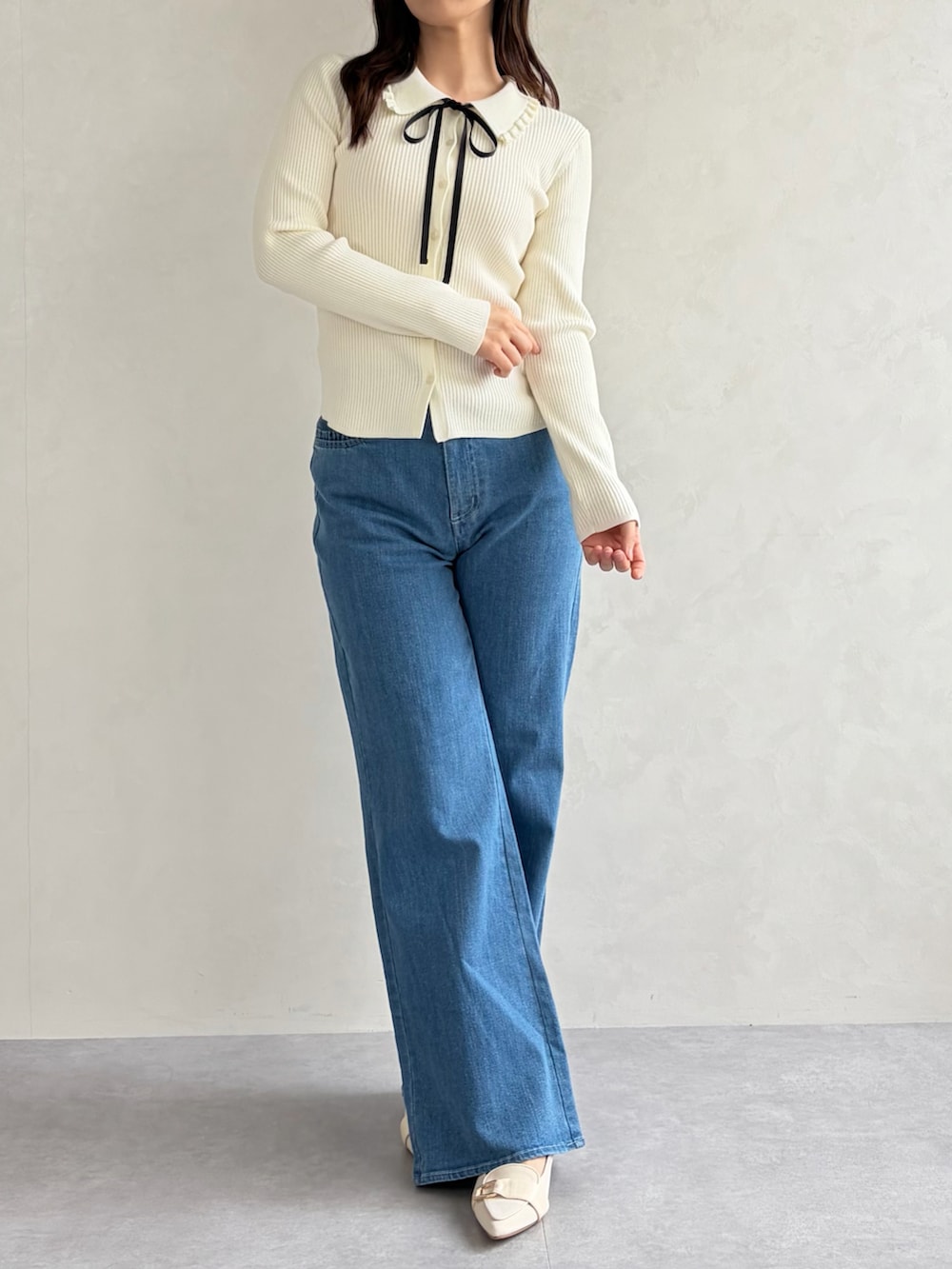 ブルー系のデニムパンツ、ホワイト系のニット/セーターを着用したレディースの春コーディネートの2枚目の写真