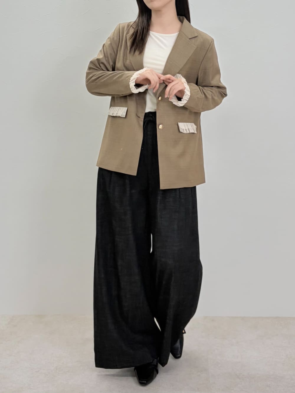 ブラック系のパンプス、ブラック系のスラックス、ブラウン系のテーラードジャケットを着用したレディースの春コーディネートの4枚目の写真