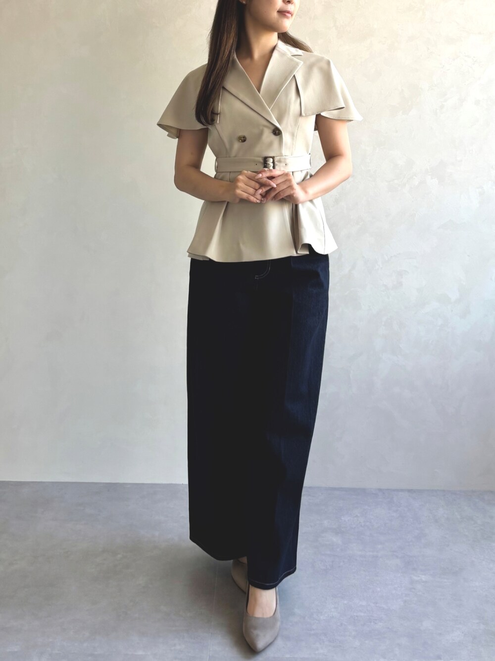 ベージュ系のベスト、ブルー系のデニムパンツ、グレー系のパンプスを着用したレディースの秋コーディネートの2枚目の写真