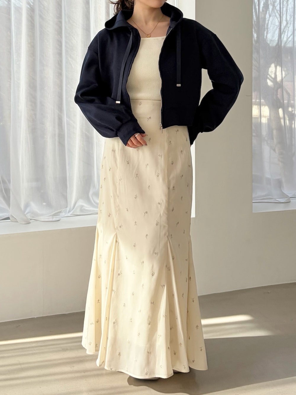 ブルー系のパーカー、ベージュ系のスニーカー、ホワイト系のスカートを着用したレディースの春コーディネートの2枚目の写真