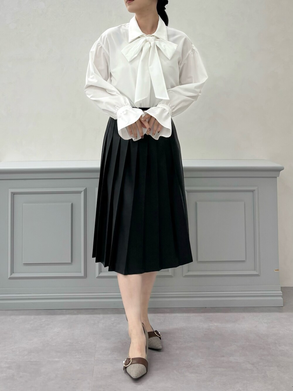 ホワイト系のシャツ/ブラウス、ベージュ系のスカート、ブラウン系のパンプスを着用したレディースの秋コーディネートの2枚目の写真