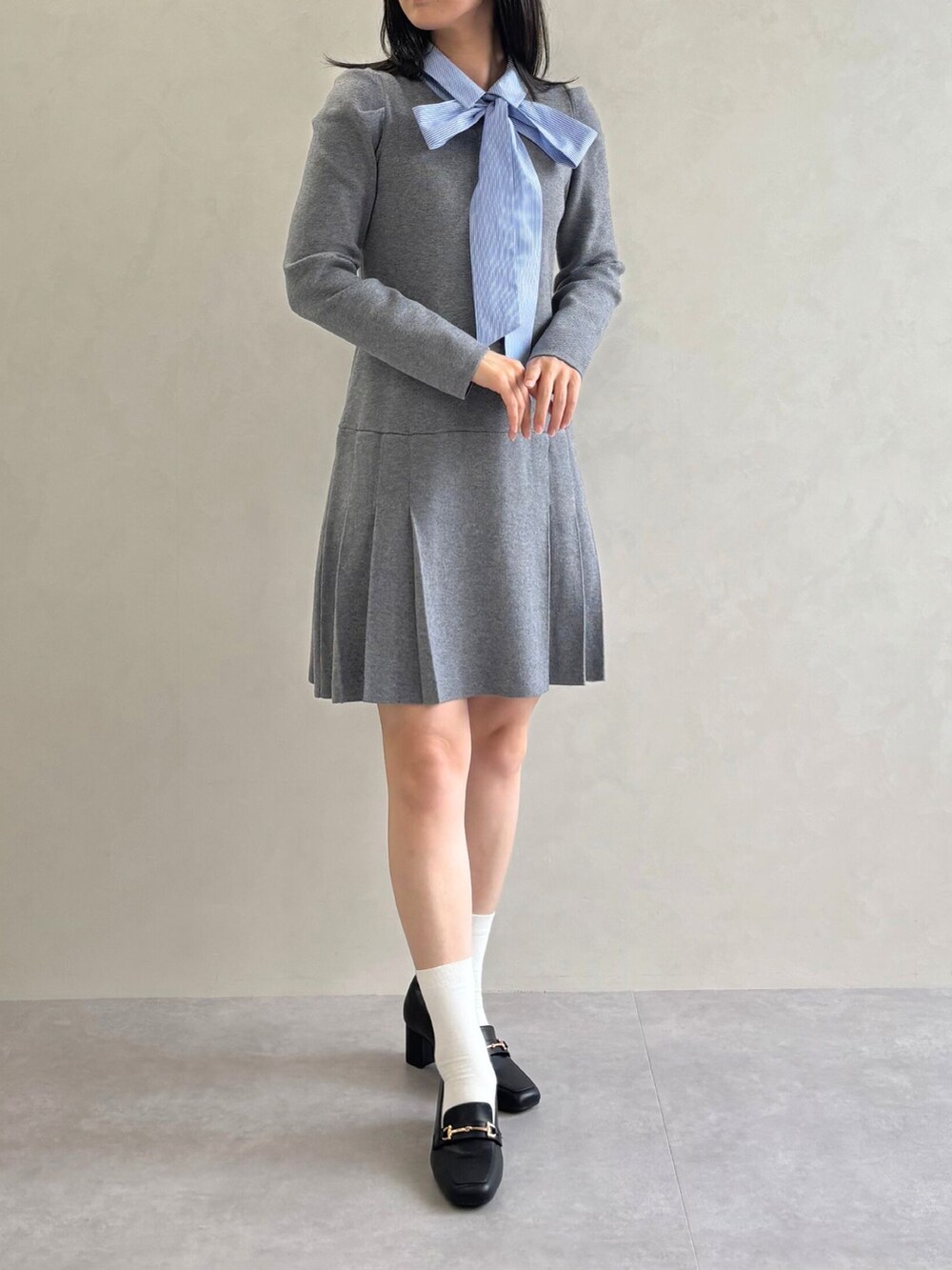 グレー系のワンピース、ブラック系のパンプスを着用したレディースの秋コーディネートの2枚目の写真