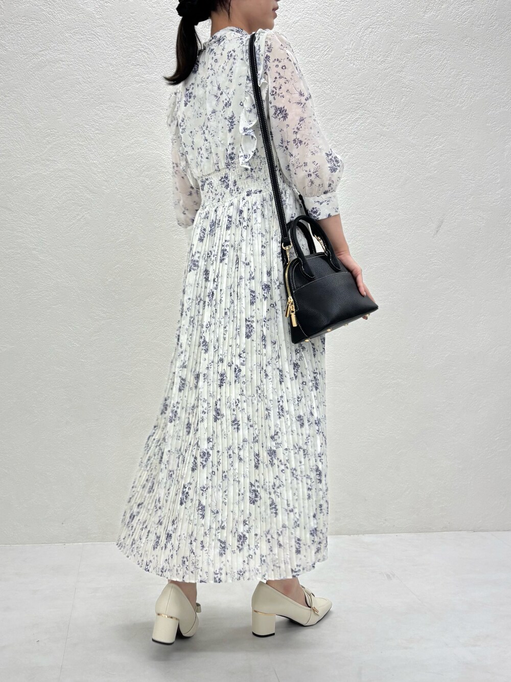 グリーン系のワンピース、ブラック系のバッグ、ベージュ系のパンプスを着用したレディースの秋コーディネートの4枚目の写真