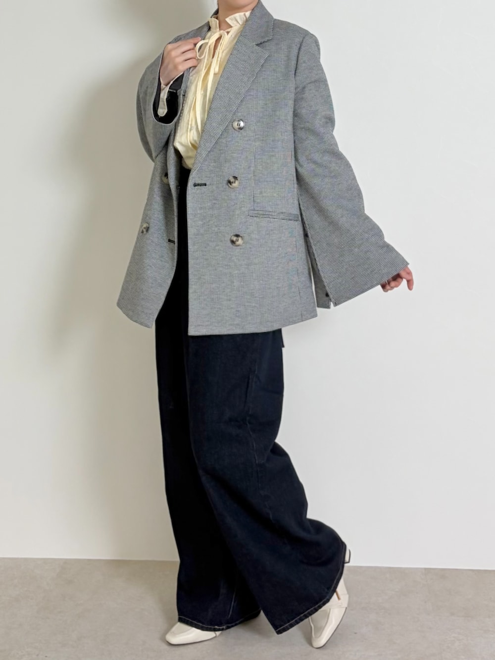 ブルー系のデニムパンツ、ブラック系のパンプス、ブラック系のテーラードジャケットを着用したレディースの春コーディネートの2枚目の写真