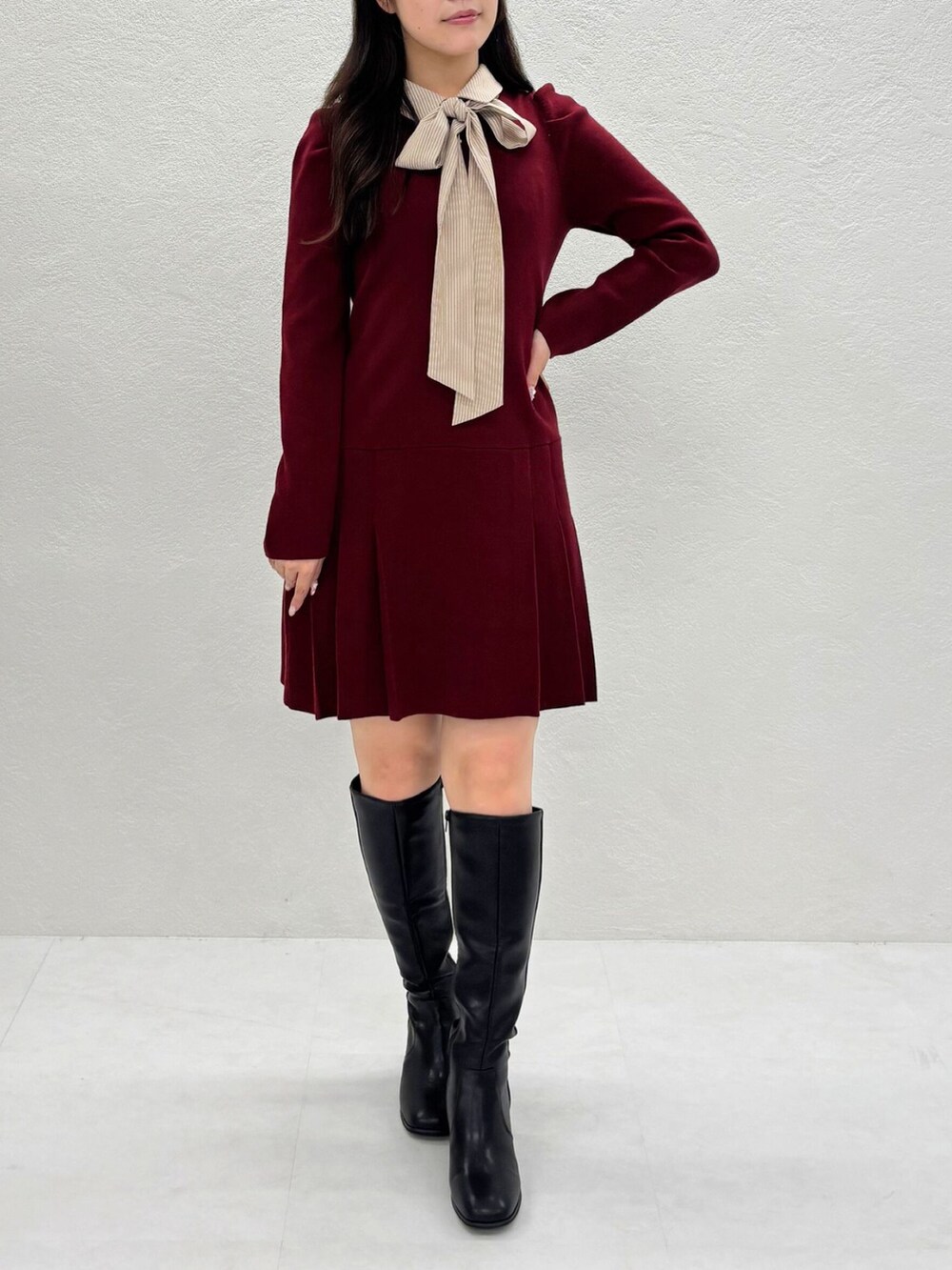 グレー系のワンピース、ブラック系のブーツを着用したレディースの秋コーディネートの2枚目の写真