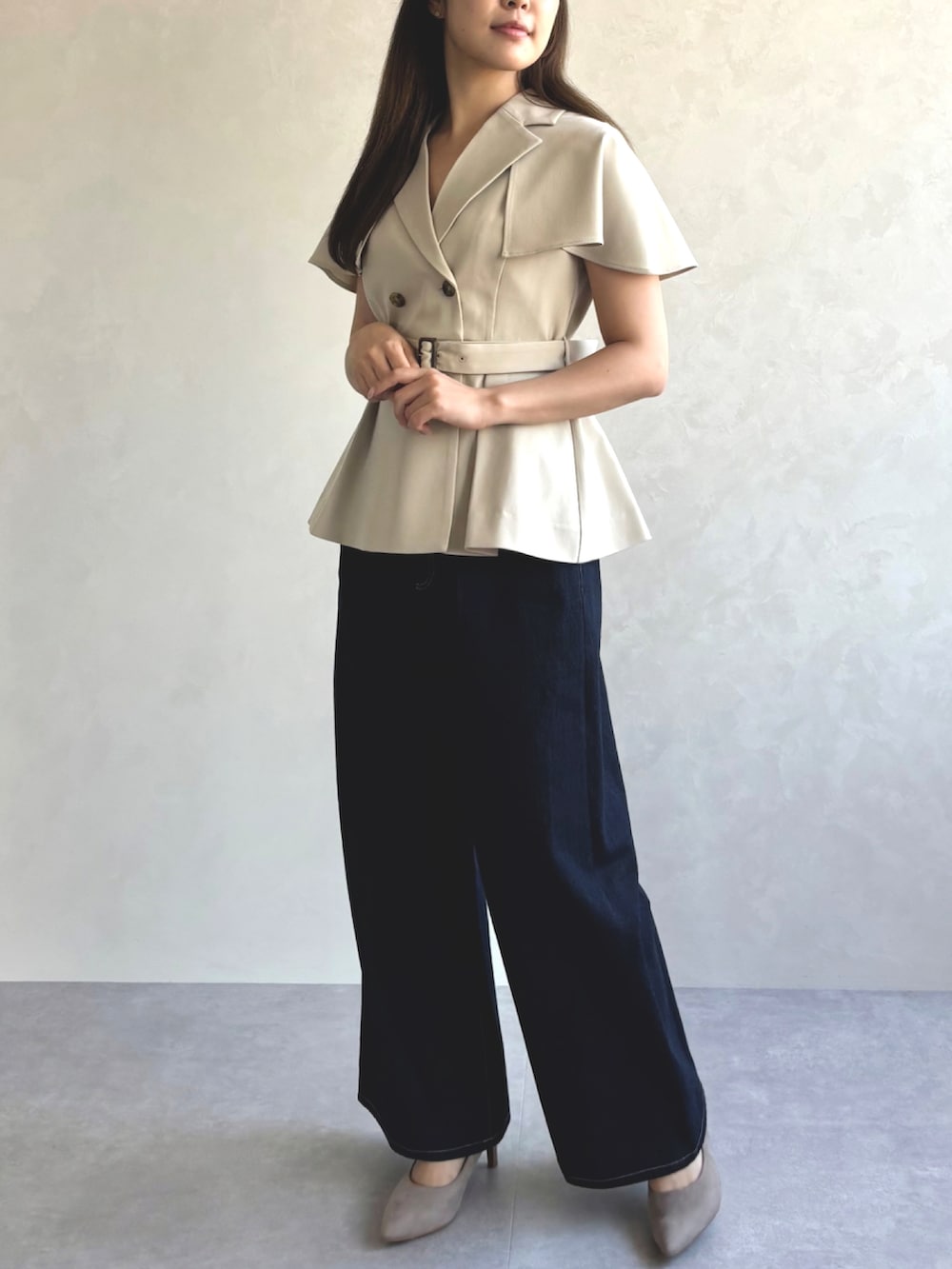 ベージュ系のベスト、ブルー系のデニムパンツ、グレー系のパンプスを着用したレディースの秋コーディネートの3枚目の写真