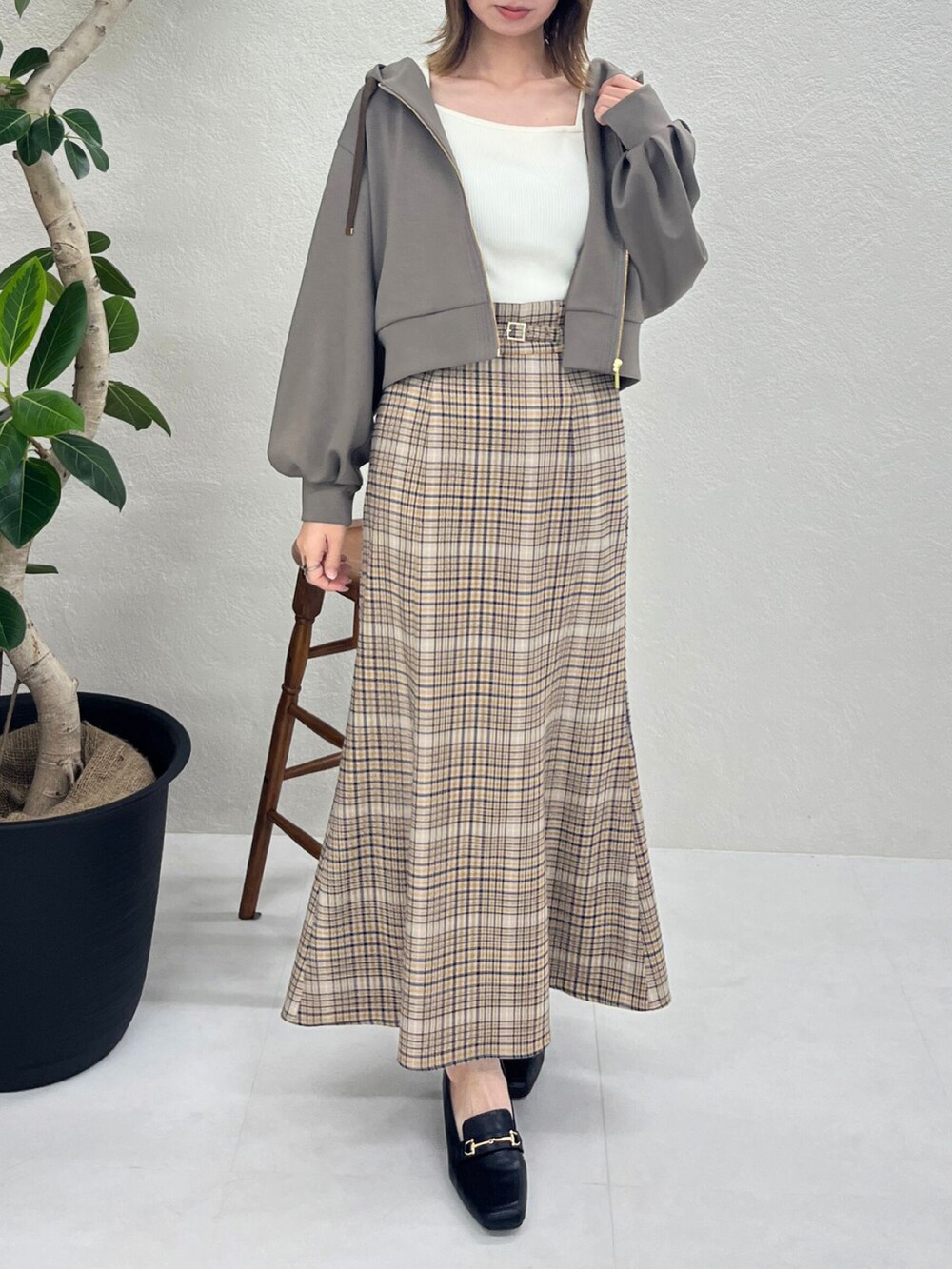 ブラウン系のパーカー、ベージュ系のスカート、ブラック系のバッグを着用したレディースの秋コーディネートの4枚目の写真