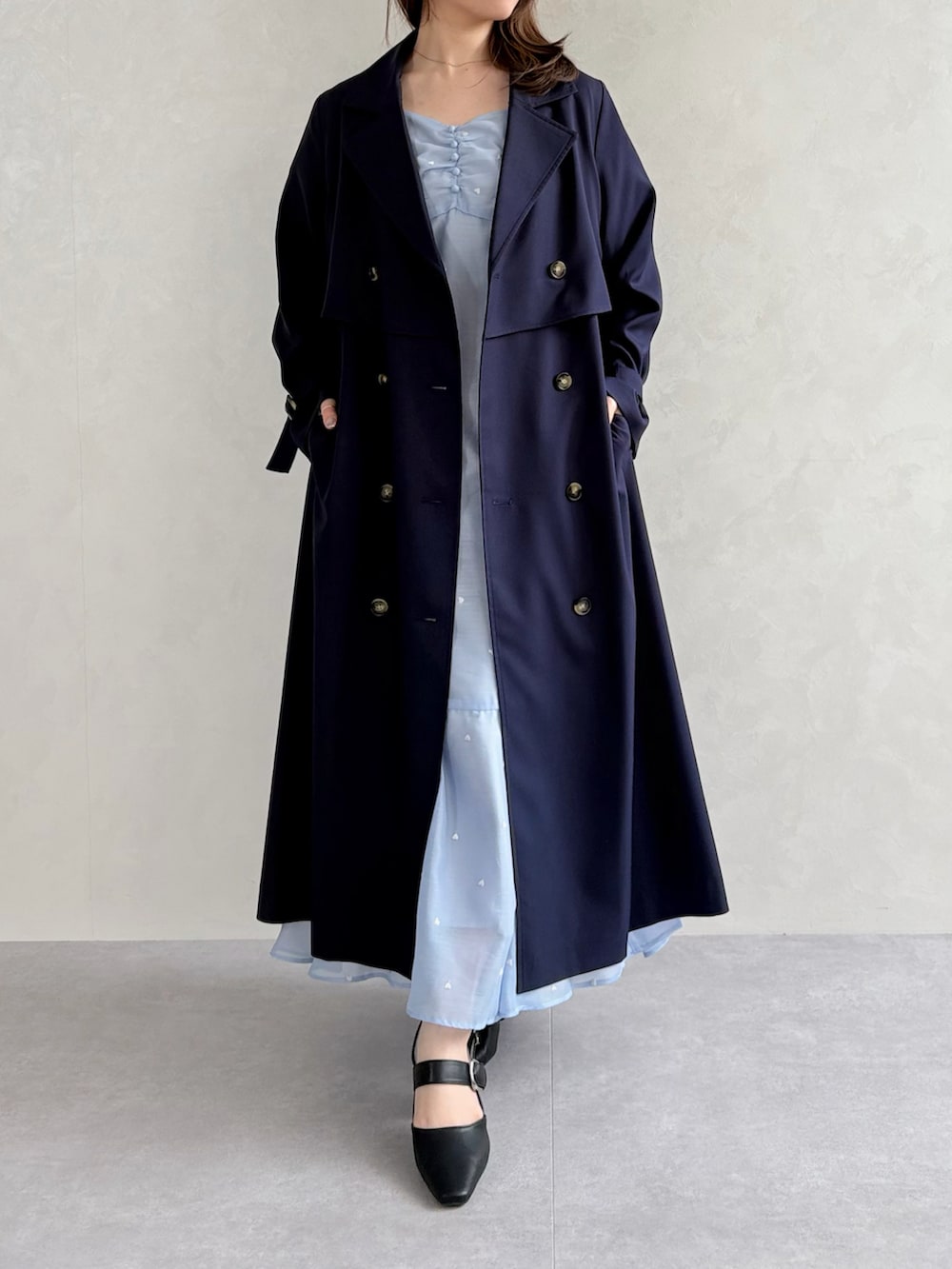 ブラック系のパンプス、ブルー系のワンピース、ブルー系のトレンチコートを着用したレディースの春コーディネートの3枚目の写真