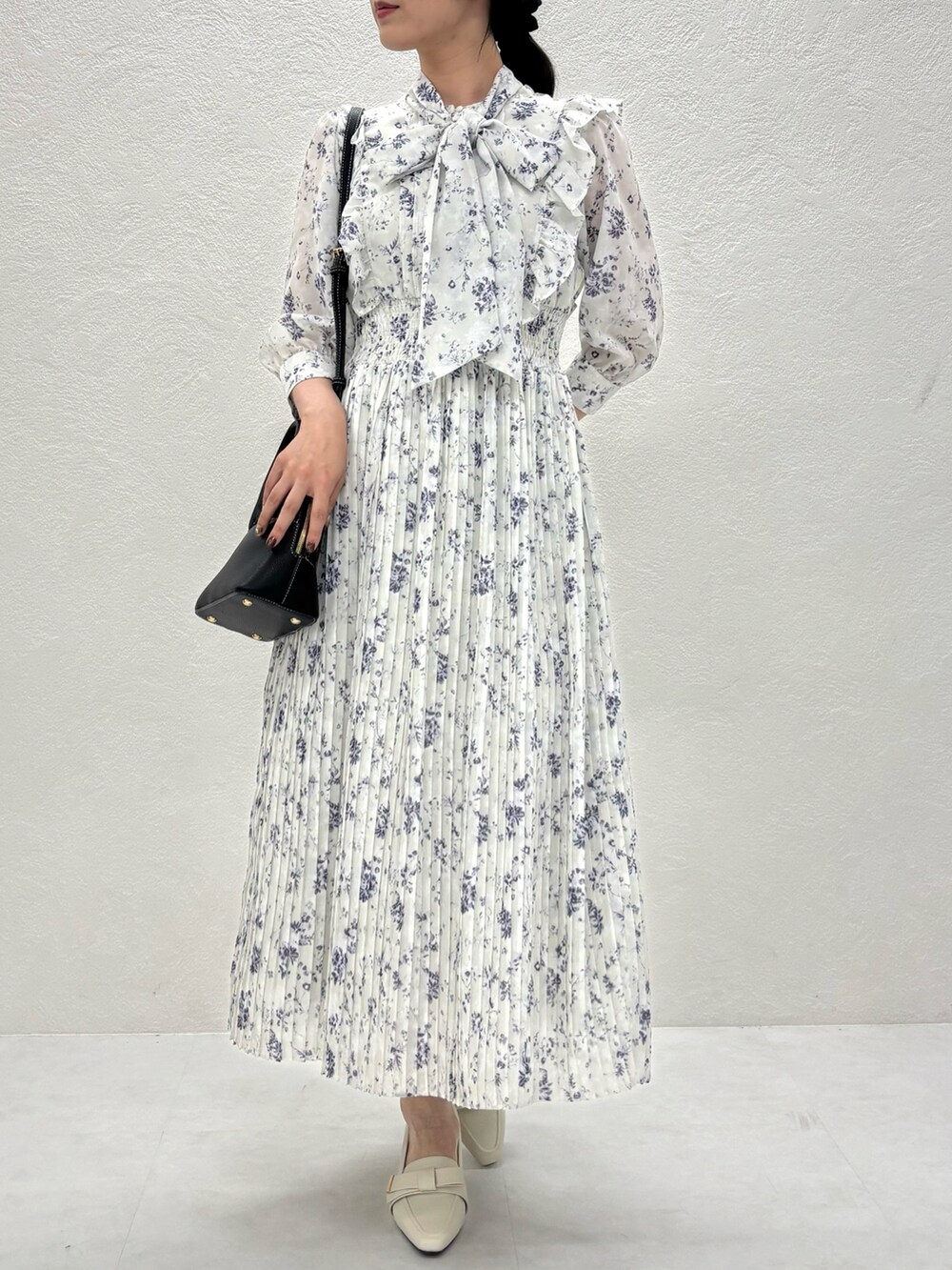 グリーン系のワンピース、ブラック系のバッグ、ベージュ系のパンプスを着用したレディースの秋コーディネートの2枚目の写真