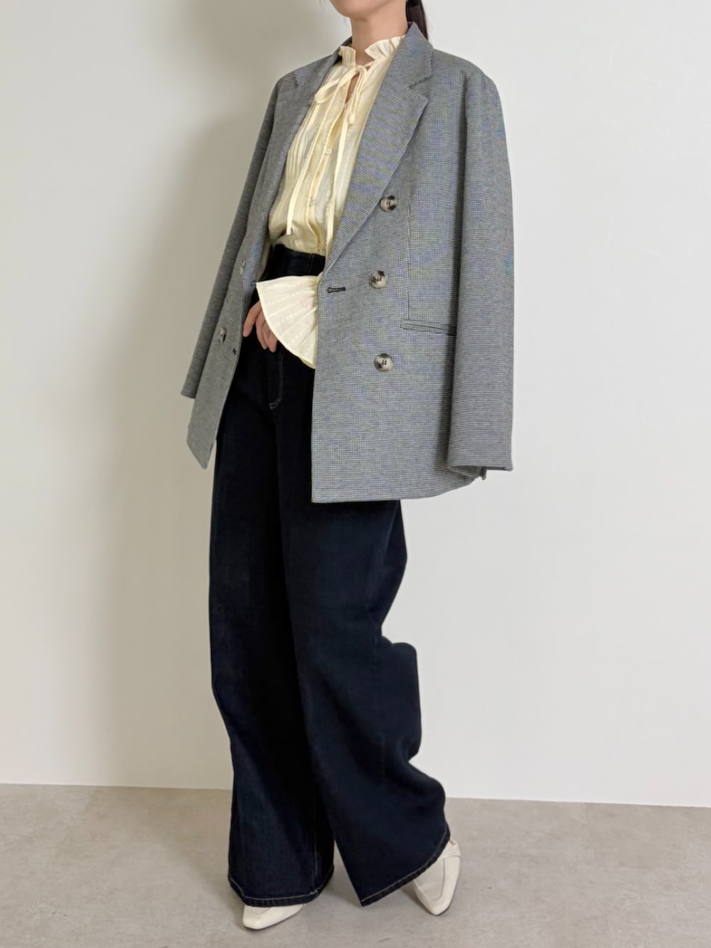 ブルー系のデニムパンツ、ブラック系のパンプス、ブラック系のテーラードジャケットを着用したレディースの春コーディネートの4枚目の写真