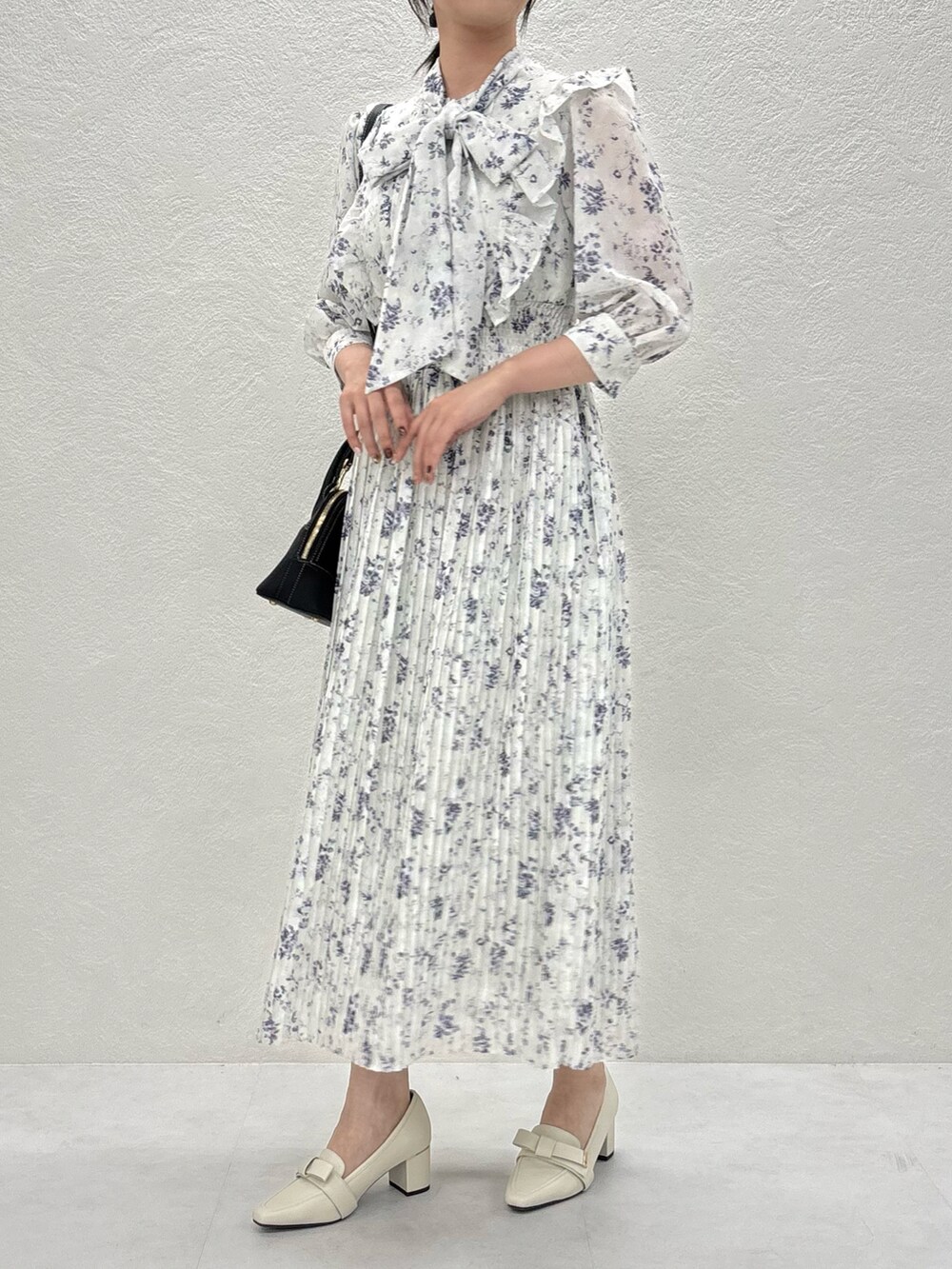 グリーン系のワンピース、ブラック系のバッグ、ベージュ系のパンプスを着用したレディースの秋コーディネートの3枚目の写真