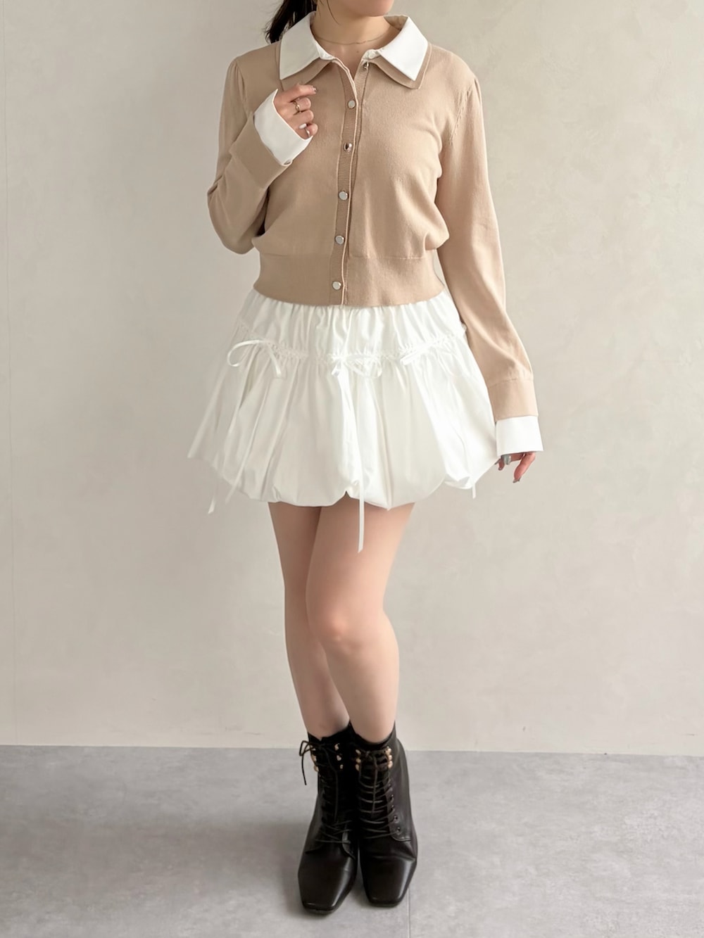 ベージュ系のニット/セーター、ブラウン系のブーツ、ホワイト系のスカートを着用したレディースの春コーディネートの3枚目の写真