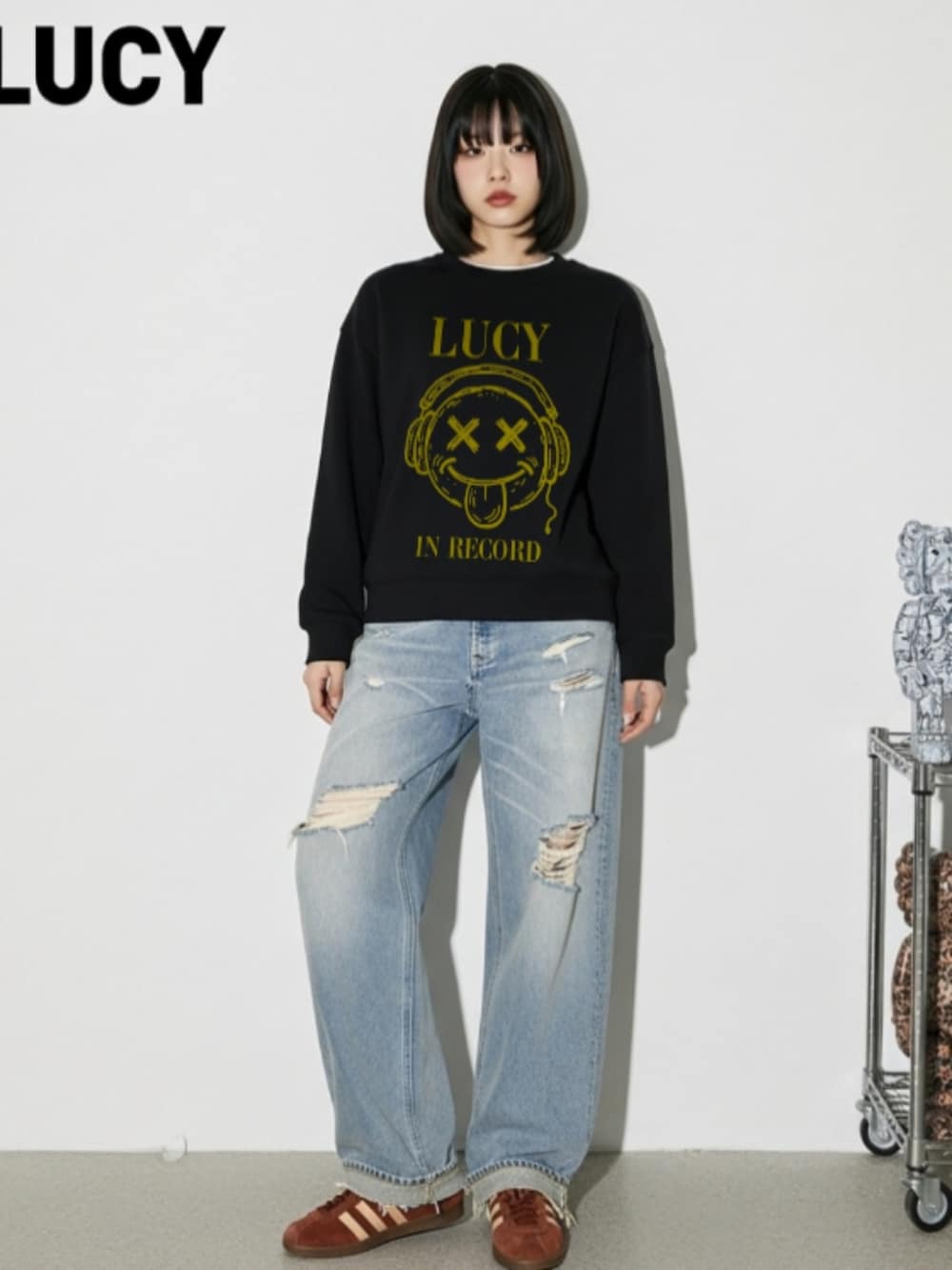 ブラウン系のスニーカー、ブルー系のデニムパンツ、ブラック系のスウェットを着用したレディースの秋コーディネートの4枚目の写真