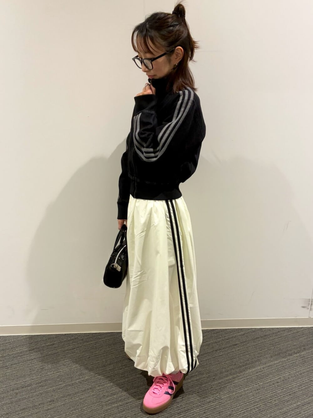 ブラック系のショルダーバッグ、ブラック系のデニムジャケット、ホワイト系のスカートを着用したレディースの冬コーディネートの2枚目の写真