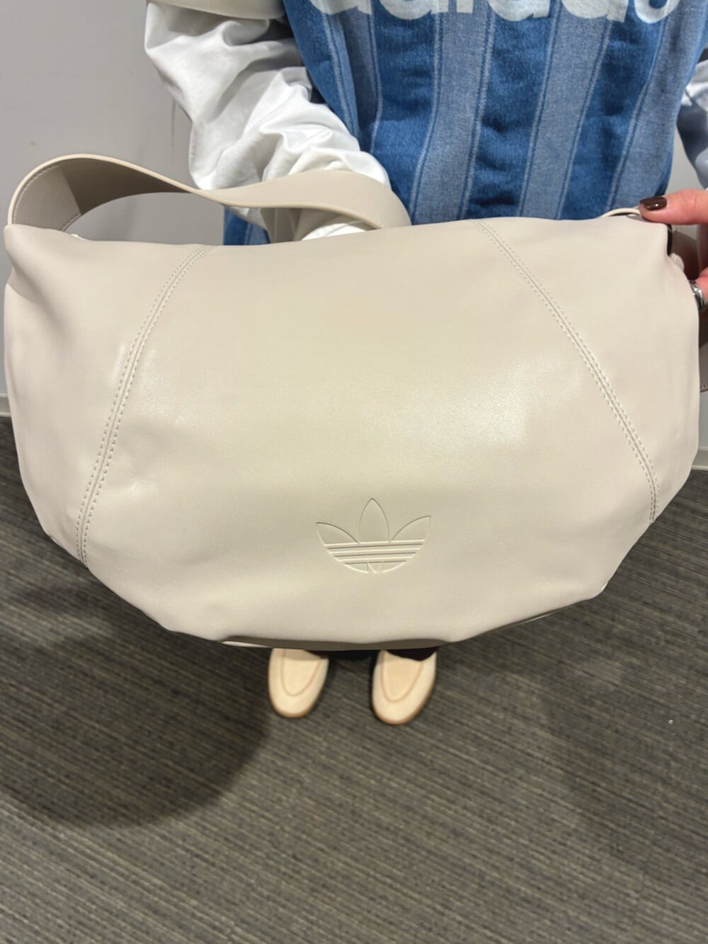 ブラウン系のショルダーバッグ、ベージュ系のスニーカー、ブルー系のジャージを着用したレディースの春コーディネートの4枚目の写真