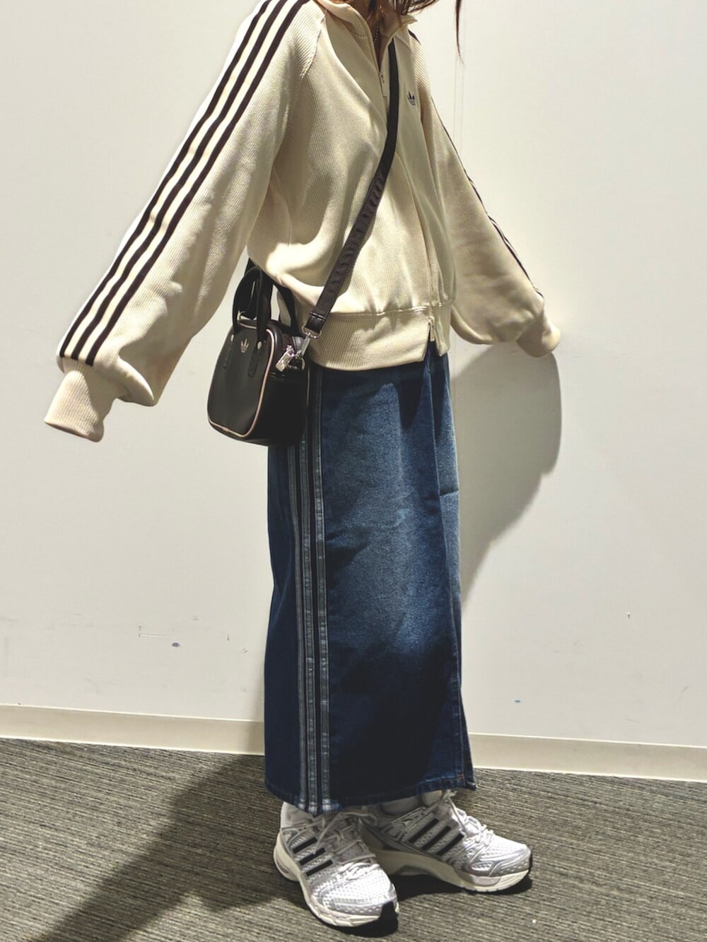 ホワイト系のジャージ、ブルー系のデニムスカート、シルバー系のスニーカーを着用したレディースの春コーディネートの2枚目の写真