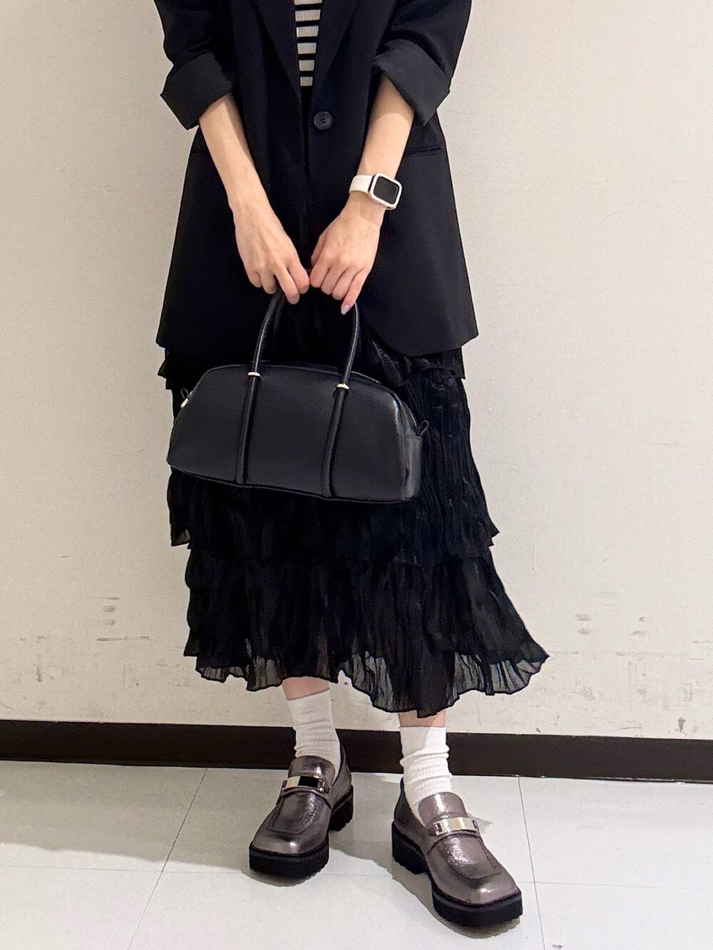 ブラック系のボストンバッグ、シルバー系のローファーを着用したレディースの冬コーディネートの4枚目の写真