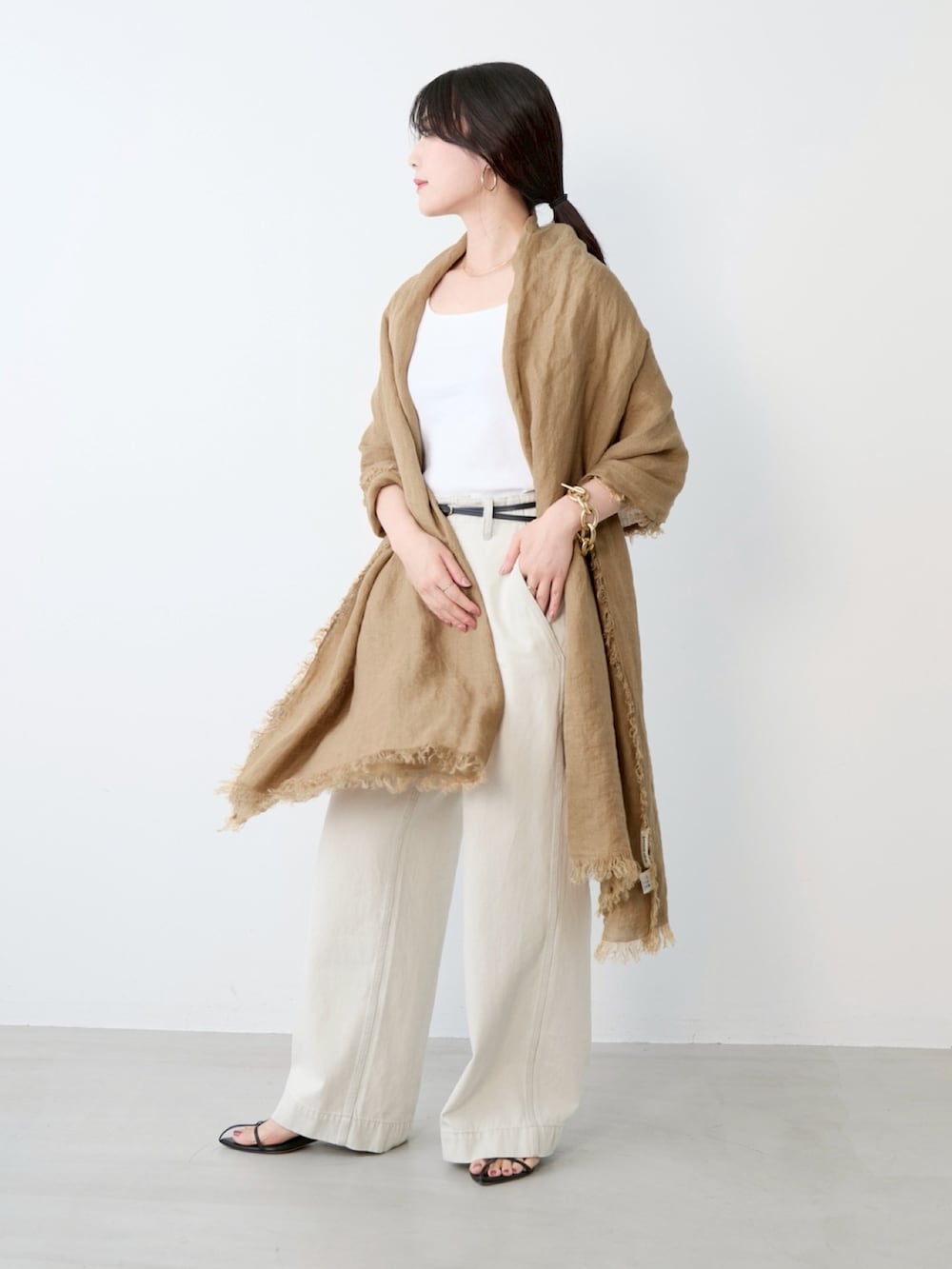 グレー系のチノパンツ、ベージュ系のストール/ショールを着用したレディースの春コーディネートの2枚目の写真