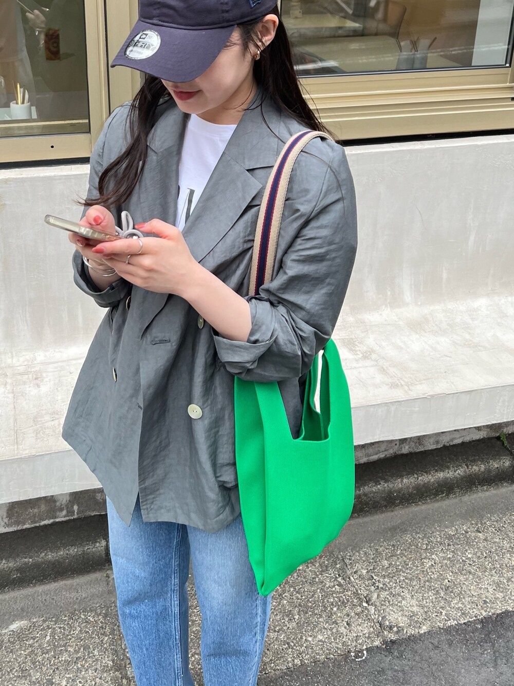 グレー系のテーラードジャケット、ホワイト系のTシャツ/カットソー、ブルー系のデニムパンツを着用したレディースの春コーディネートの5枚目の写真