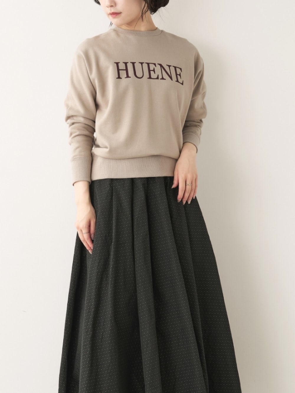 ベージュ系のスウェット、ブラック系のスカートを着用したレディースの秋コーディネートの2枚目の写真