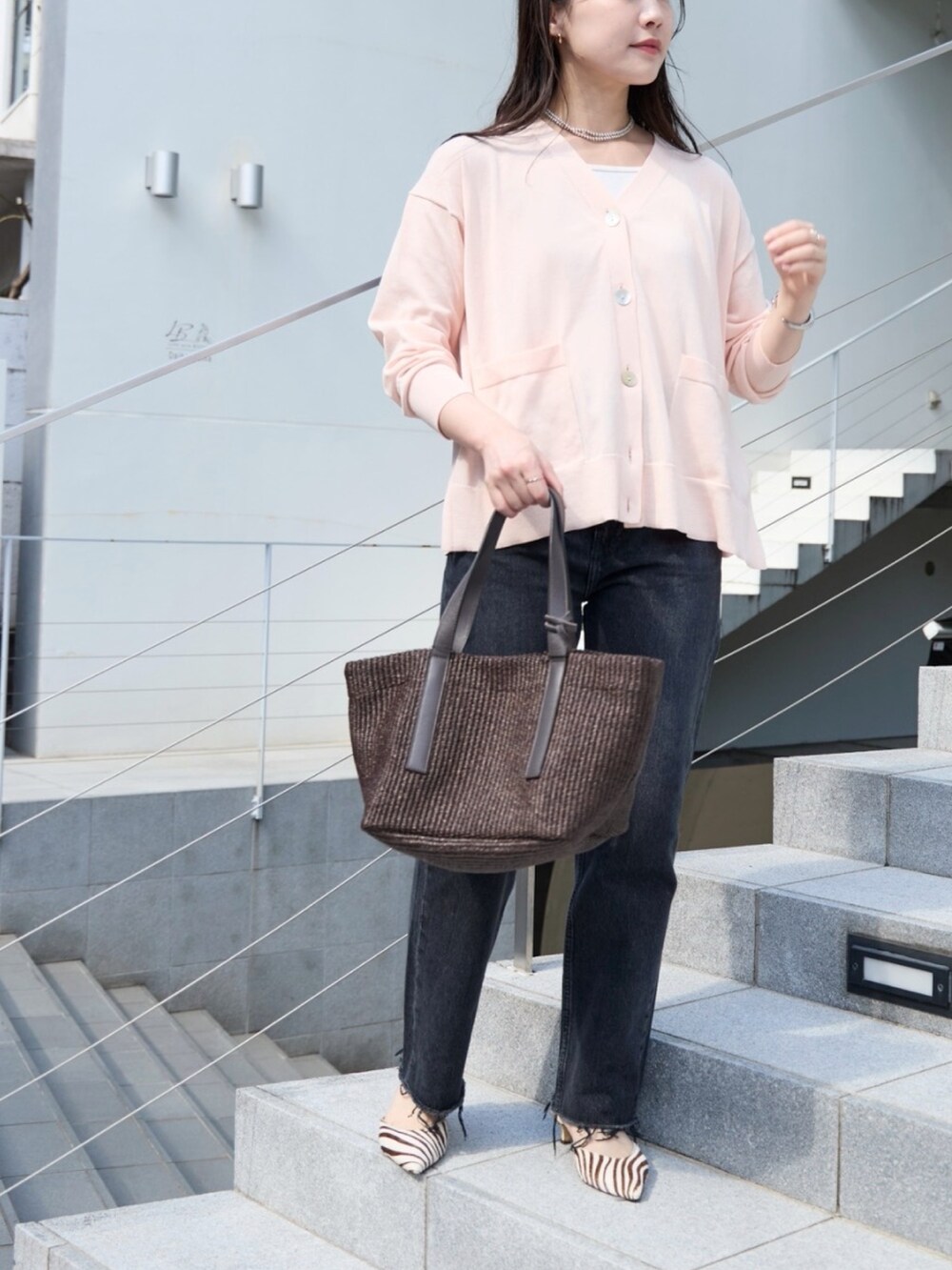 ピンク系のカーディガン/ボレロ、ブラック系のデニムパンツ、ブラウン系のトートバッグを着用したレディースの春コーディネートの2枚目の写真