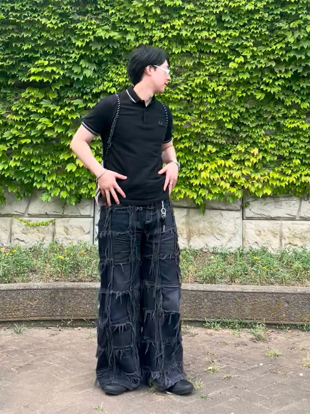 ブラック系のデニムパンツ、グレー系のバックパック/リュック、ブラック系のポロシャツを着用したメンズの夏コーディネートの2枚目の写真