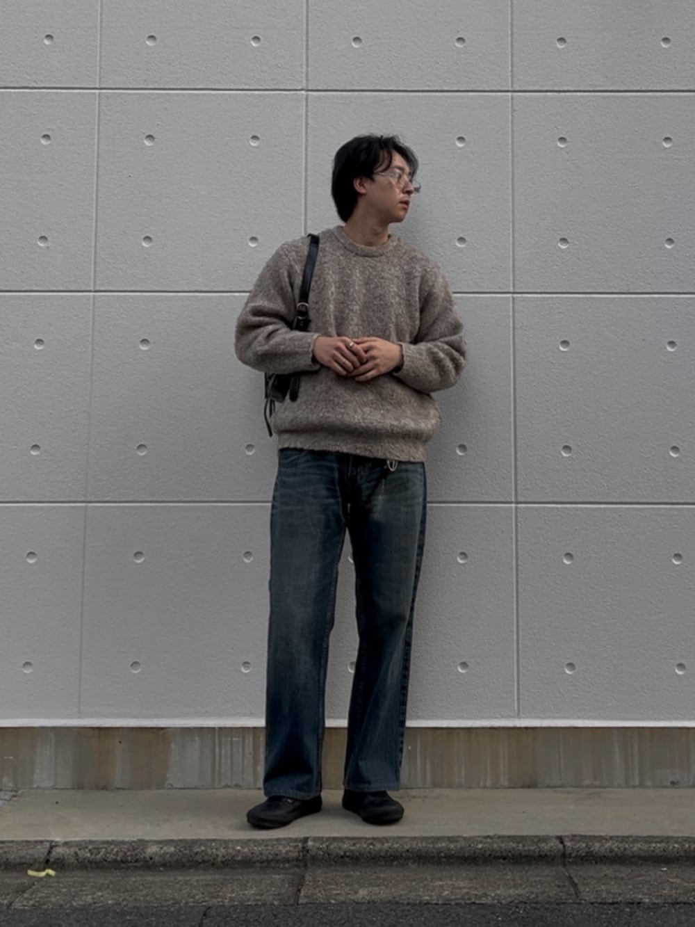 ブラウン系のニット/セーター、ブルー系のデニムパンツ、ブラック系のショルダーバッグを着用したメンズの秋コーディネートの2枚目の写真