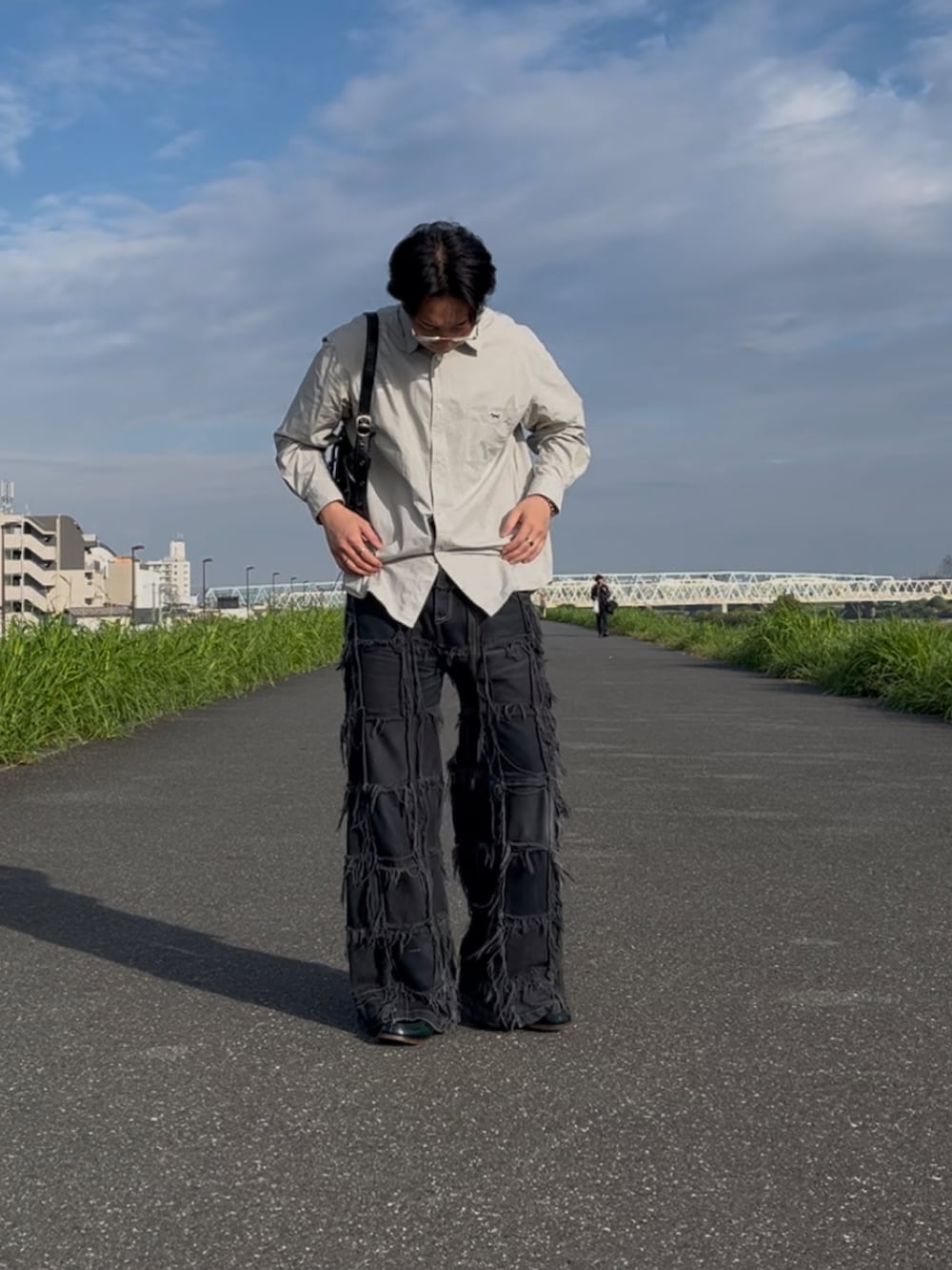 ブラック系のデニムパンツ、ブラック系のショルダーバッグ、グリーン系のローファーを着用したメンズの秋コーディネートの2枚目の写真